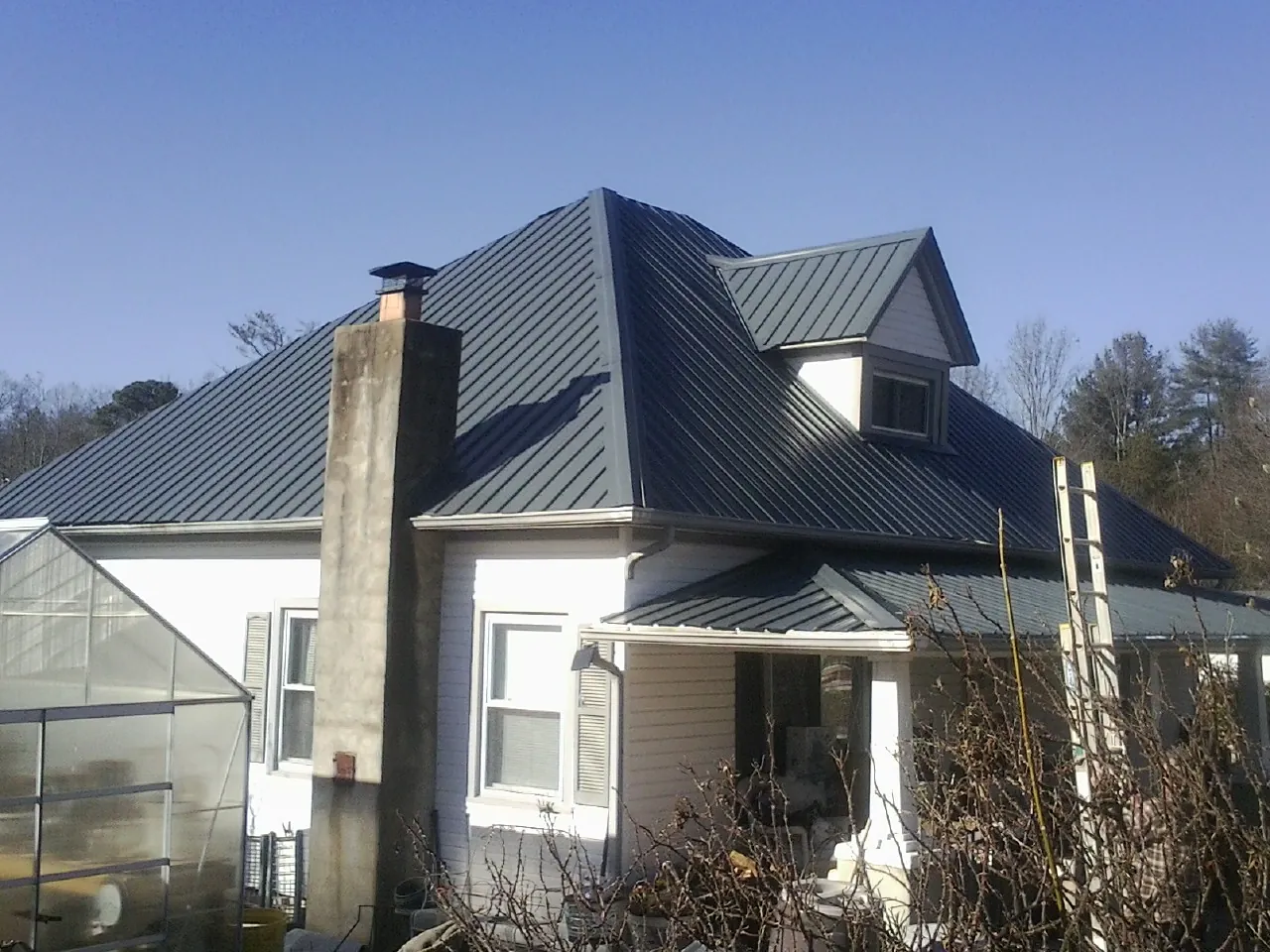 Dark blue standing seam metal roof on a white farmhouse with dormer — Slate & Tile Roof Repair by Roofing Brothers in Rosendale