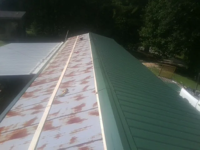 Old rusted panels beside newly installed green metal roofing — Wind Damage Roof Repair by Roofing Brothers in Rosendale
